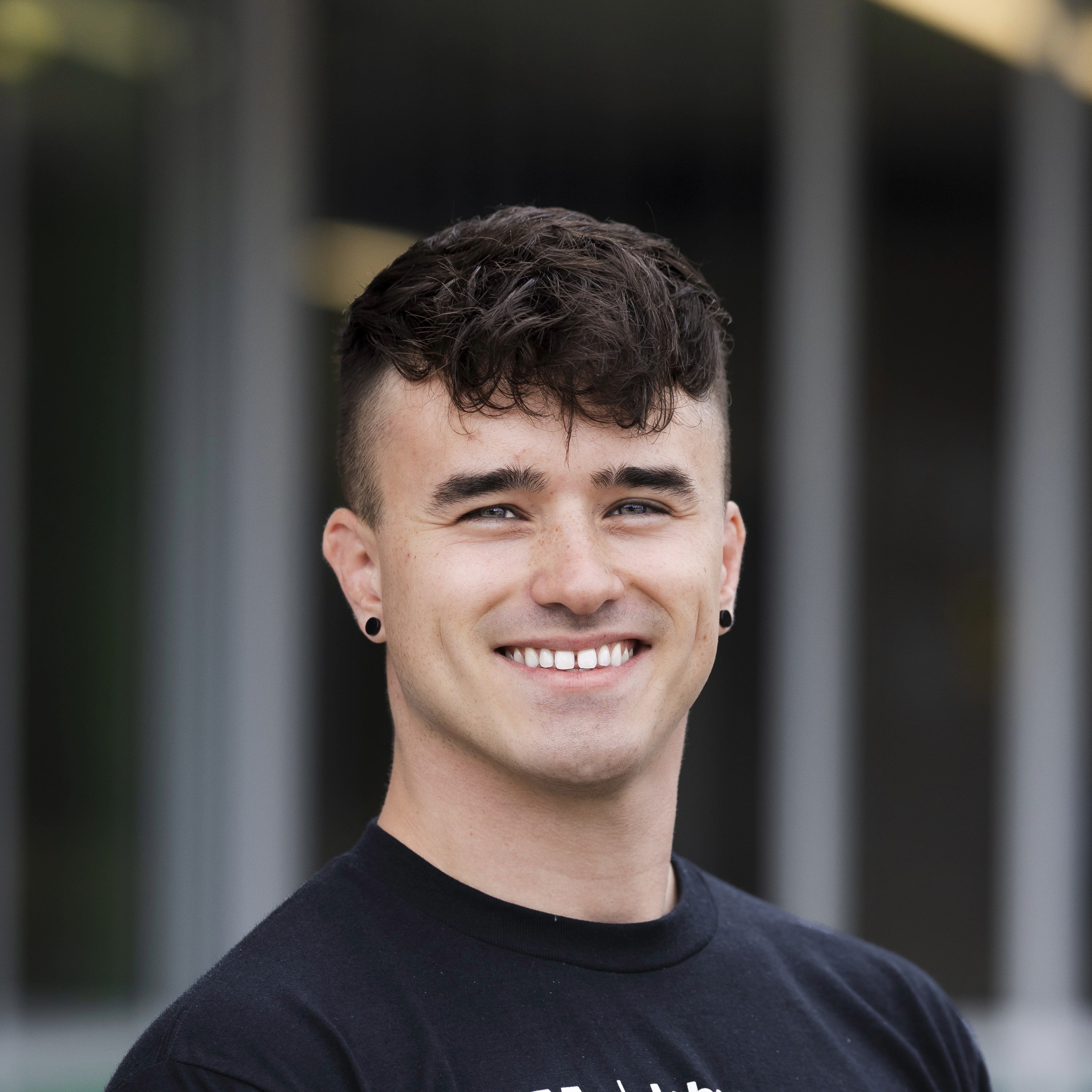 headshot photo of Tristan in a black shirt